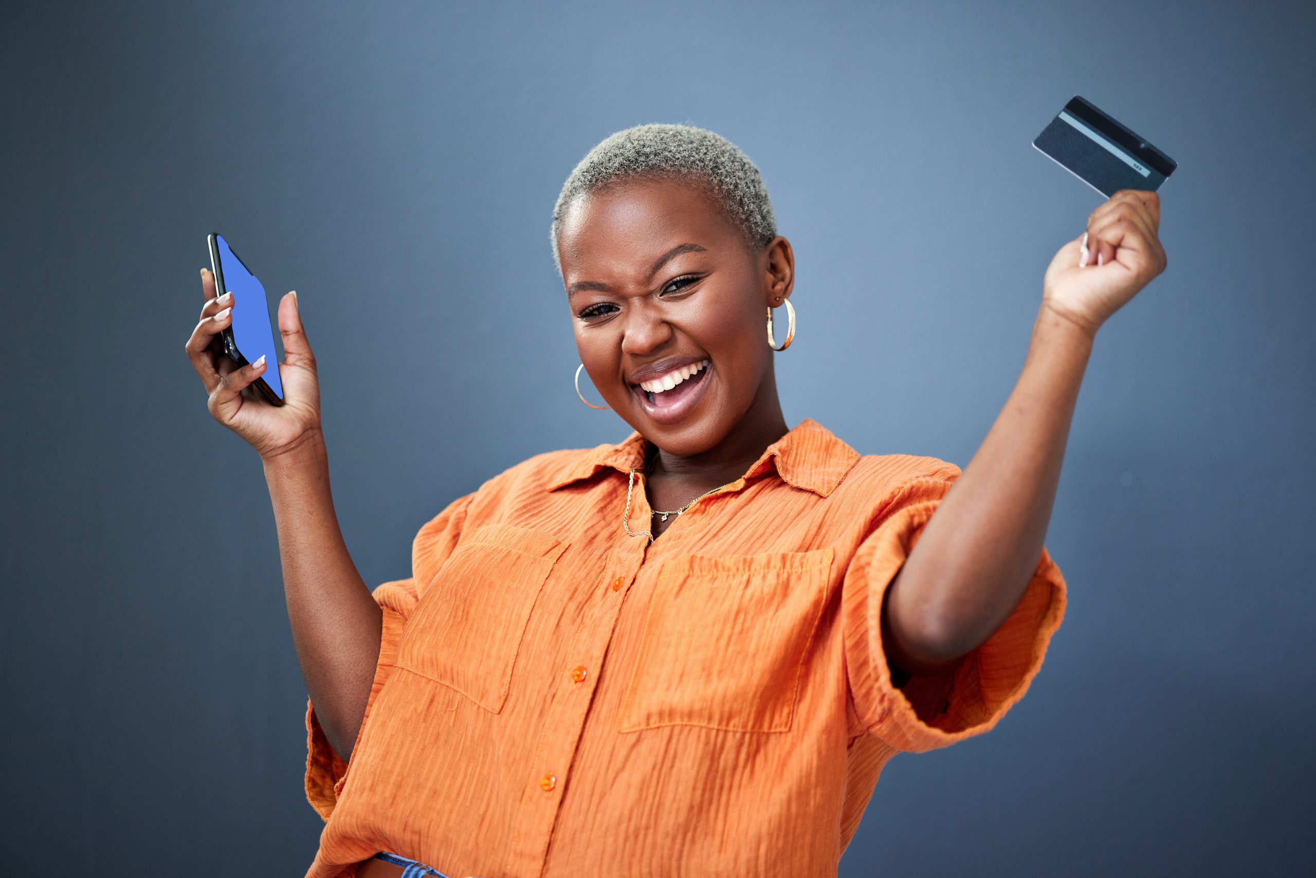 Winner, phone and credit card with a black woman online shopping in studio on a gray background. Mobile, ecommerce and wow with a happy young female shopper in celebration of deal or sale success